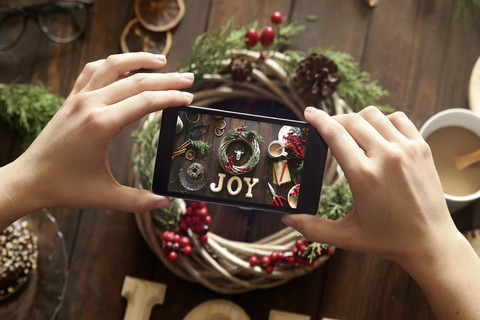 Woman's hands taking picture of self-made Advent wreath with smartphone stock photo