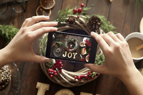 Woman's hands taking picture of self-made Advent wreath with smartphone - RTBF00487