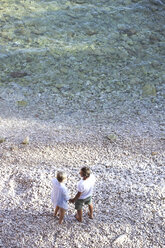 Draufsicht auf ein älteres Paar, das Hand in Hand am Strand steht - HAPF01017