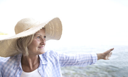 Happy mature woman wearing straw hat on the beach - HAPF01036