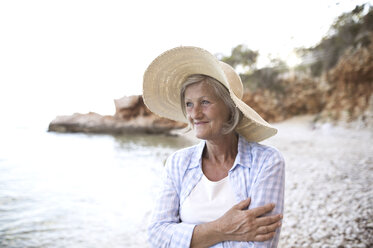 Portrait of happy mature woman wearing straw hat on the beach - HAPF01037