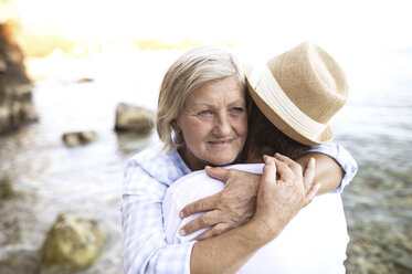 Portrait of content woman hugging her husband in front of the sea - HAPF01043