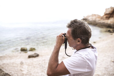 Senior man taking picture on the beach - HAPF01045