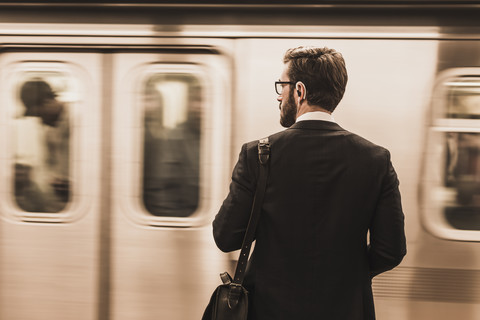 Junger Geschäftsmann wartet am Bahnsteig einer U-Bahn-Station, lizenzfreies Stockfoto