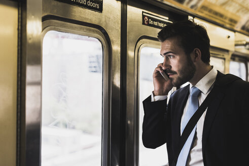 Junger Geschäftsmann fährt mit der U-Bahn und benutzt ein Smartphone - UUF09011