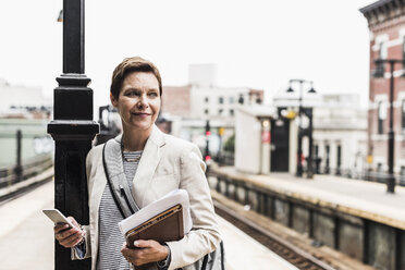 Mature woman using smart phone at commuter train station - UUF09040