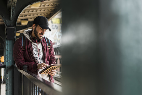 Young man waiting for metro, weraing headphones, using digital tablet stock photo