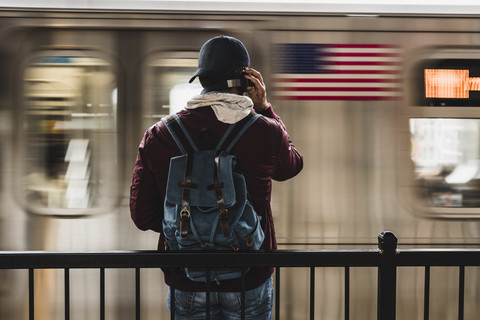 Junger Mann, der am Bahnsteig auf die U-Bahn wartet und Kopfhörer trägt, lizenzfreies Stockfoto