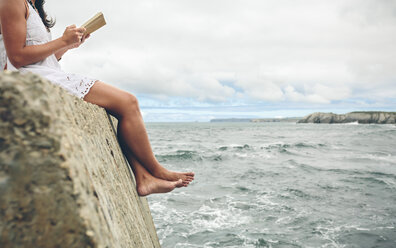 Barfüßige Frau sitzt auf dem Pier und liest ein Buch, Teilansicht - DAPF00460