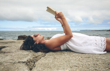 Frau liegt auf dem Pier und liest ein Buch - DAPF00462