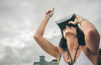 Lächelnde Frau mit Virtual-Reality-Brille im Freien - DAPF00469