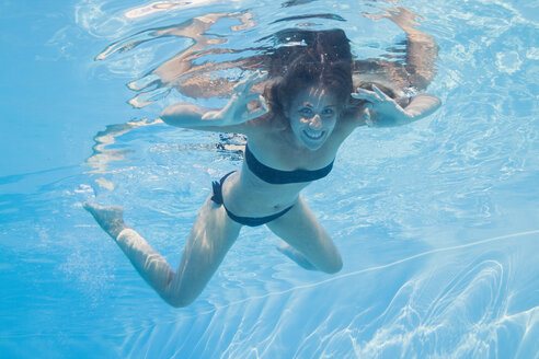 Lächelnde junge Frau unter Wasser in einem Pool - MAUF00919