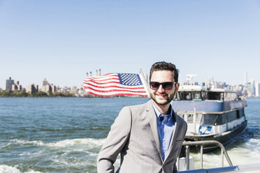 USA, New York City, lächelnder Geschäftsmann auf Fähre auf dem East River - UUF09056