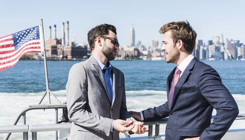 USA, New York City, two businessmen talking on ferry on East River stock photo