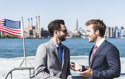 USA, New York City, zwei Geschäftsleute unterhalten sich auf einer Fähre auf dem East River - UUF09059