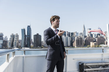 USA, New York City, Geschäftsmann telefoniert auf einer Fähre auf dem East River - UUF09066