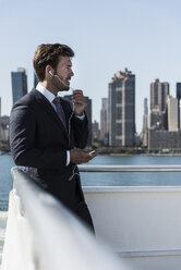 USA, New York City, Geschäftsmann telefoniert auf einer Fähre auf dem East River - UUF09069