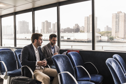 Two businessmen with document talking on passenger deck of a ferry stock photo