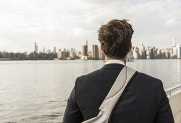 USA, New York City, Rückenansicht eines Mannes am East River mit Blick auf Manhattan - UUF09105