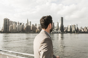 USA, New York City, Rückenansicht eines Mannes am East River mit Blick auf Manhattan - UUF09115