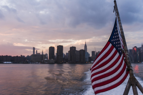 USA, New York City, US flag on ferry on East River with skyline of Manhattan in background stock photo