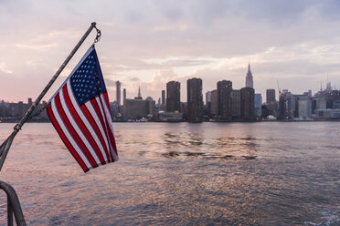 USA, New York City, US-Flagge auf einer Fähre auf dem East River mit der Skyline von Manhattan im Hintergrund - UUF09119