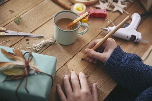 Woman writing on Christmas present tag, close-up - RTBF00511