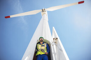 Engineer inspecting wind turbine, using wrench - ZEF11512