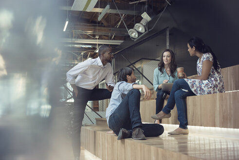 Young business people discussing, sitting on stairs - WESTF21895