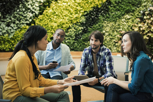 Junge Geschäftsleute diskutieren vor einer grünen Pflanzenwand - WESTF21913