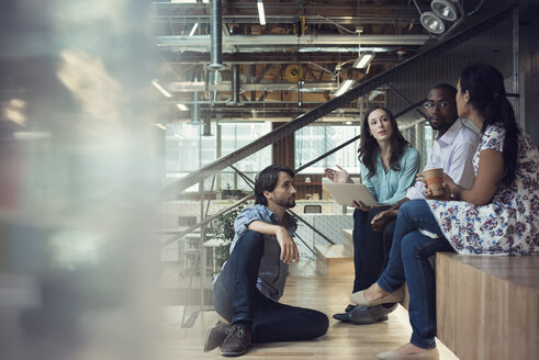 Young business people discussing, sitting on stairs - WESTF21949