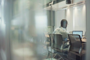 Businessman sitting in office, using laptop - WESTF21964