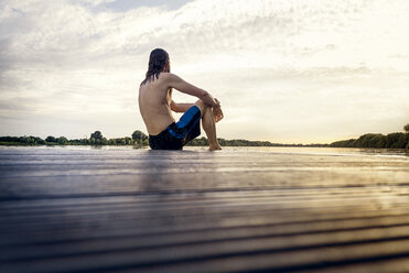 Man sitting on jetty at the water - BMAF00282