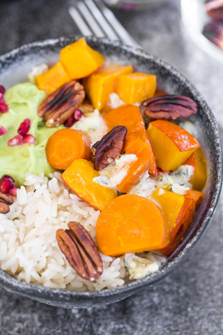 Bowl of autumnal salad with carrots, pumpkin, sweet potatoes, pecan, guacamole, pomegranate and rice stock photo