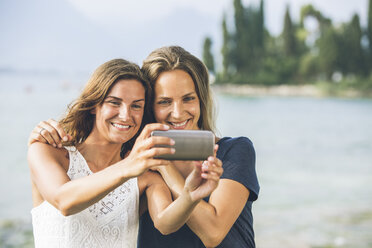 Italien, Gardasee, zwei junge Frauen machen ein Selfie - SBOF00273