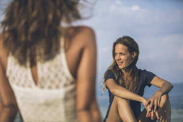 Italien, Gardasee, zwei junge Frauen sitzen am Seeufer - SBOF00279