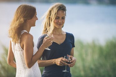 Italien, Gardasee, zwei junge Frauen am Seeufer mit einem Glas Wein - SBOF00283