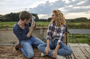 Mann fotografiert Frau auf Pick-up-Truck - FMKF03172