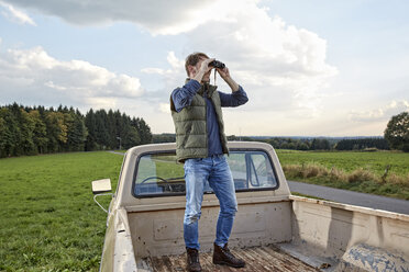 Mann steht auf einem Pick-up-LKW und schaut durch ein Fernglas - FMKF03176