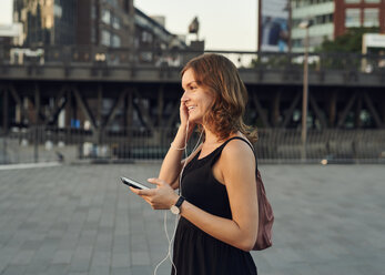 Germany, Young woman in Hamburg using smart phone - WHF00008