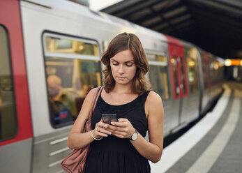 Deutschland, Junge Frau mit Smartphone auf Erkundungstour in Hamburg - WHF00015