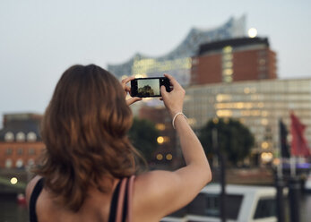 Deutschland, Junge Frau in Hamburg beim Fotografieren mit ihrem Smartphone - WHF00017