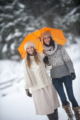 Porträt von zwei Freunden mit gelbem Regenschirm im Winter - HHF05468