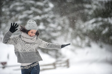 Happy woman wearing knitwear dancing in the snow - HHF05471