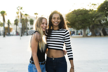 Portrait of two happy young women on square at sunset - KKAF00011