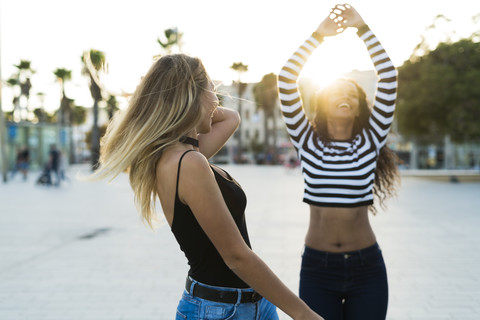 Two young women having fun on square at sunset stock photo
