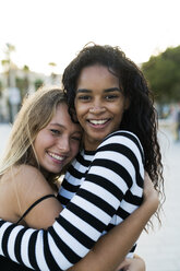 Two happy young women hugging outdoors - KKAF00014