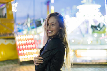 Happy young woman on a funfair at night - KKAF00035