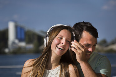 Glückliches junges Paar mit gemeinsamen Kopfhörern - JTLF00122