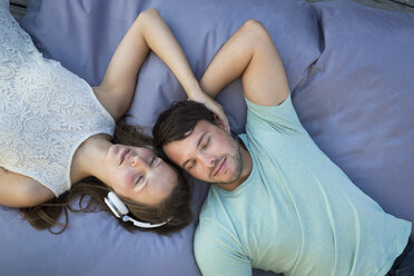 Young couple in love relaxing together on beanbag - JTLF00123